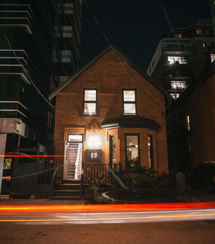 North & Navy's brick heritage house on Nepean Street lit up at night, with traffic light trails passing in front