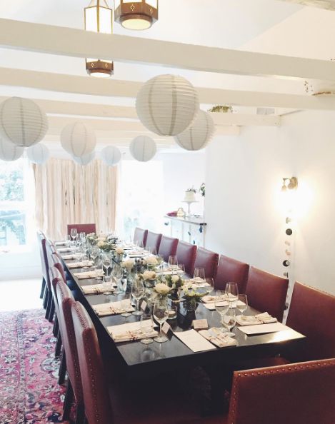 The private dining room set for a long-table event, with paper lanterns and a patterned rug