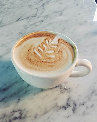 Cappuccino with leaf latte art on a marble counter