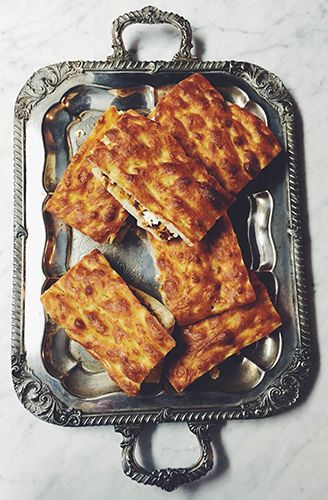 Slices of focaccia stacked on an antique silver tray